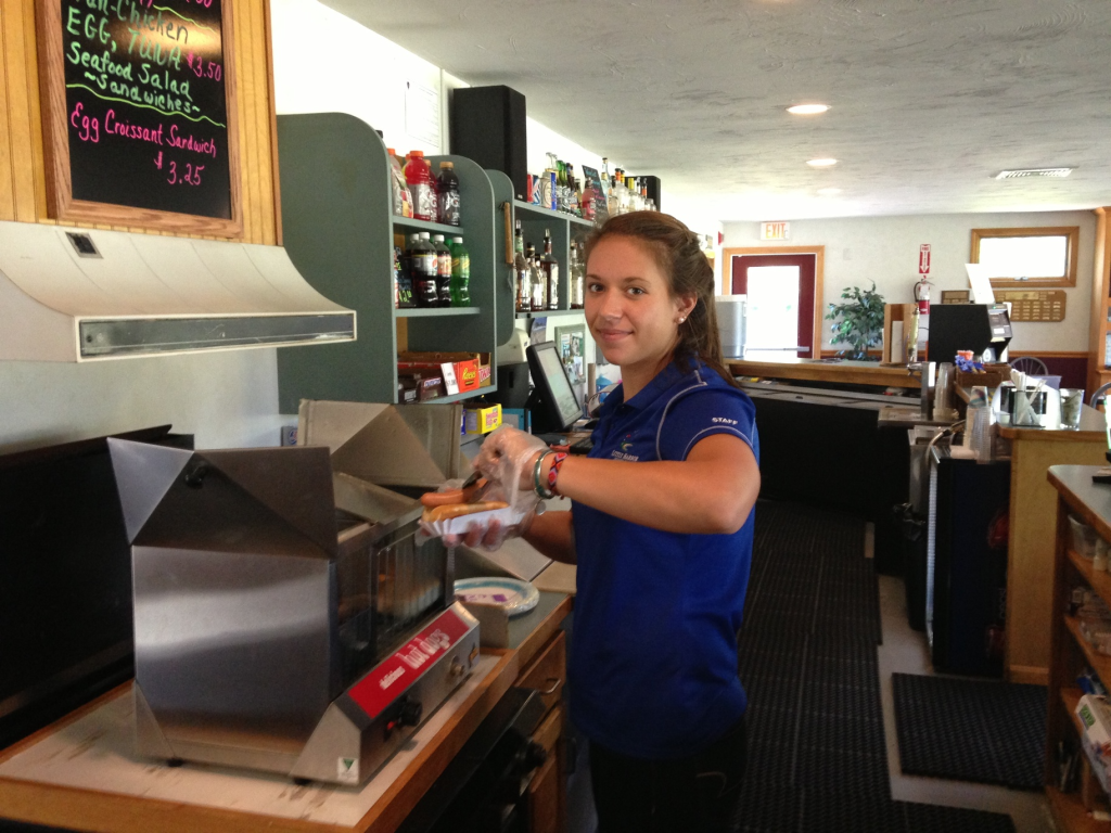 worker preparing a hot dog for a guest